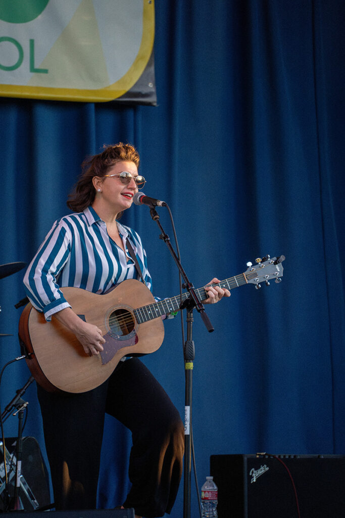 Feale musician on stage singing with guitar at Bennaroo